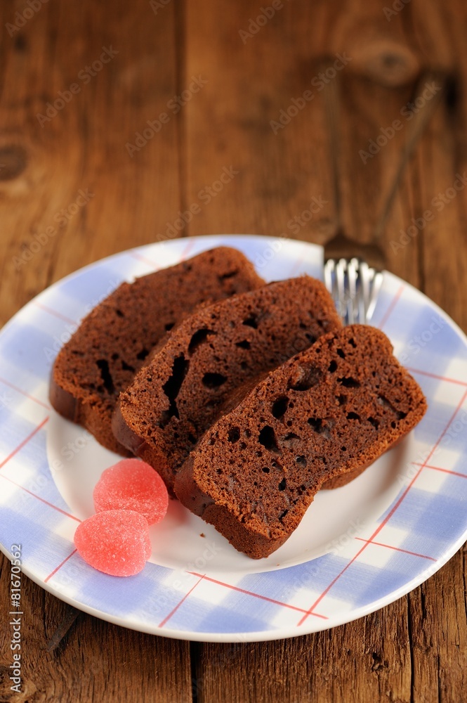 Pieces of homemade chocolate cake with pink candies on wooden ba Pieces of homemade chocolate cake with pink candies on wooden ba