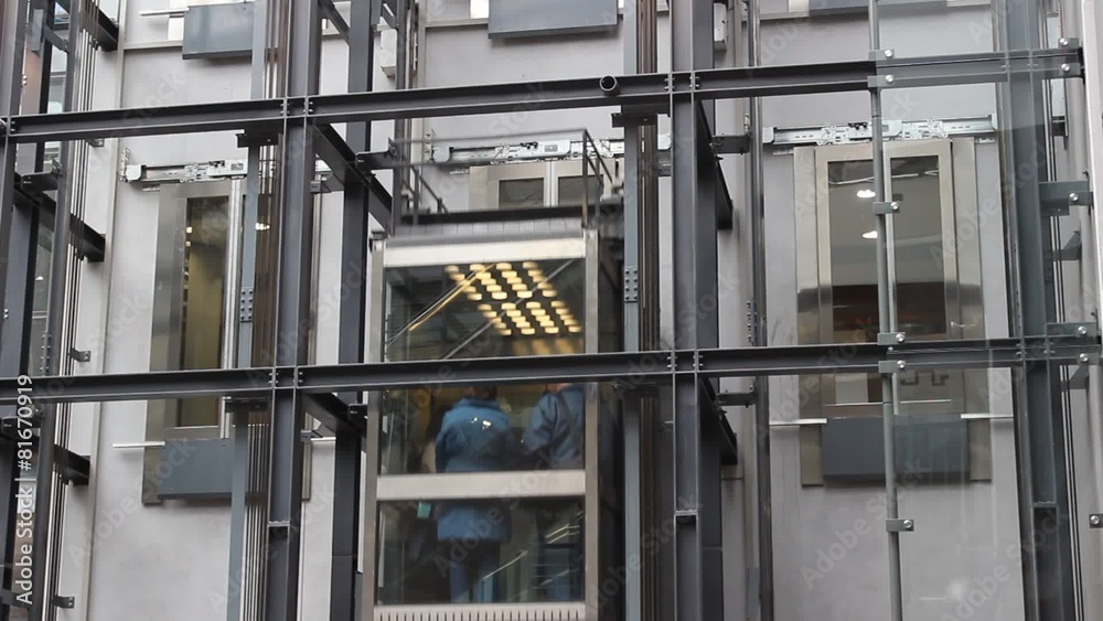 Panoramic elevators lifts in a shopping mall with people Panoramic elevators lifts in a shopping mall with people