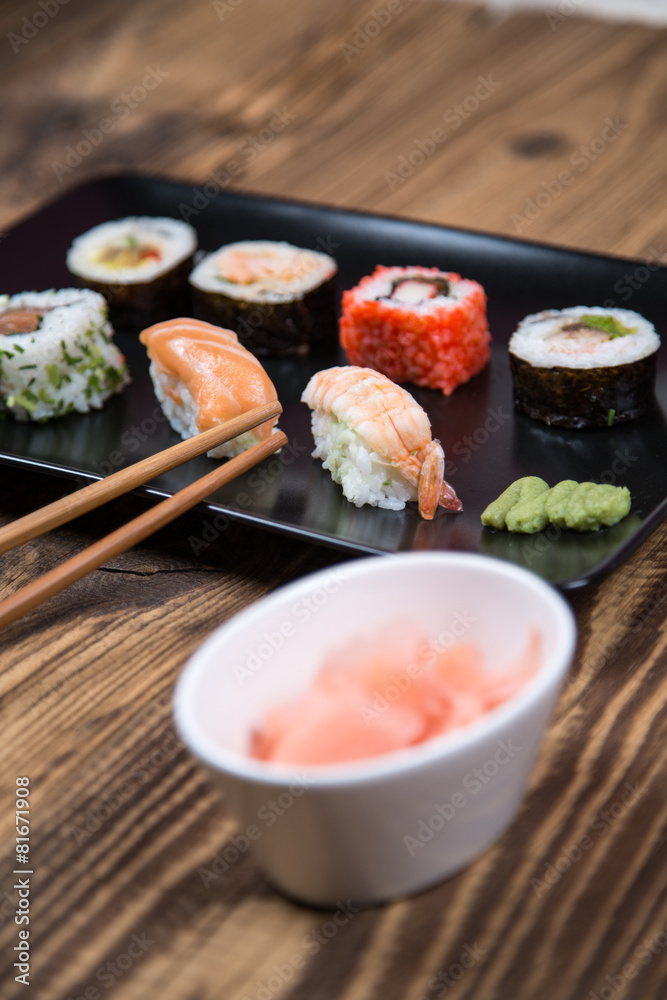 Sushi pieces collection with bamboo chopsticks, isolated on wooden table Sushi pieces collection with bamboo chopsticks, isolated on wooden table