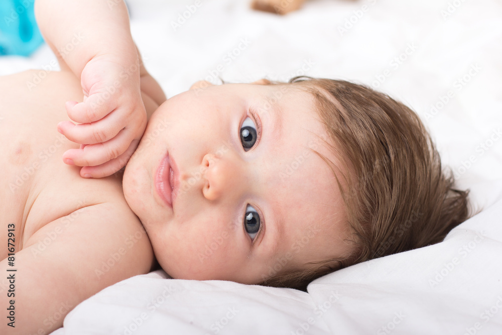 Portrait of a naked child. A child on a white bed Portrait of a naked child. A child on a white bed