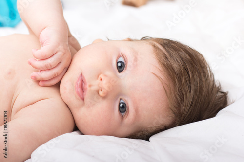 Portrait of a naked child. A child on a white bed