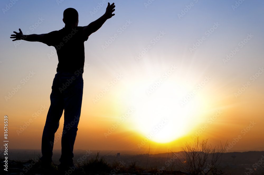 man arms outstretched to the side at sunset