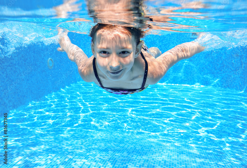 Happy girl swims in pool underwater, active kid swimming