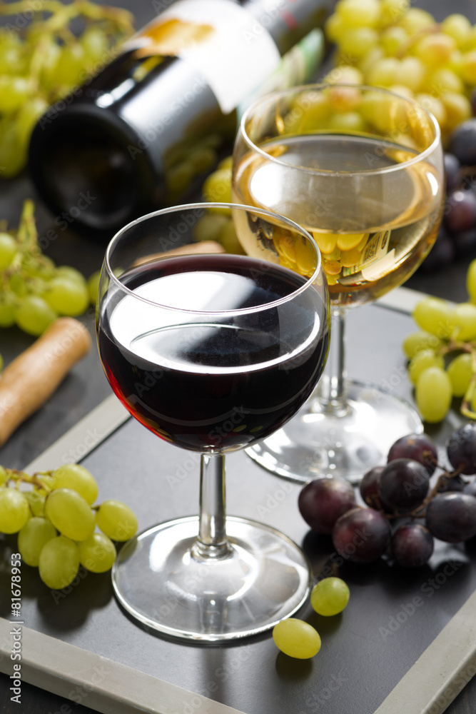 Fototapeta premium red and white wine in glasses, fresh grapes in the background