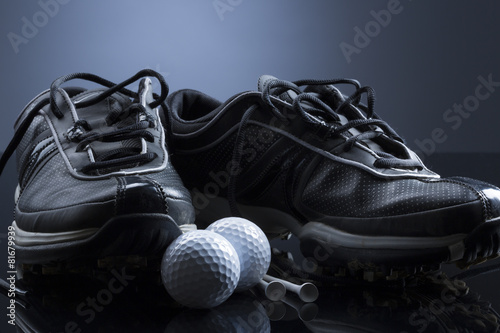 Golf balls, tees and shoes isolated on dark blue background.