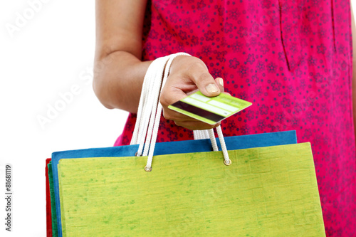 Female hand holding shopping bags and credit card on white backg