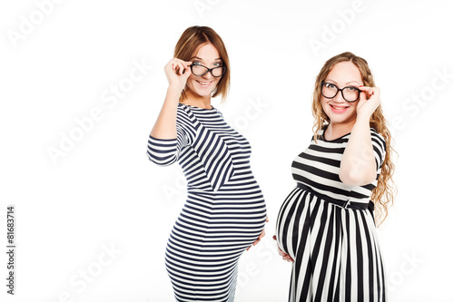 two happy pregnant women is glasses touch their belly photo