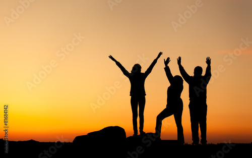 Silhouette of a happy family with arms raised up at the sunset