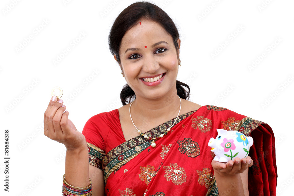 Traditional Indian woman holding a piggy bank and rupee coin Traditional Indian woman holding a piggy bank and rupee coin