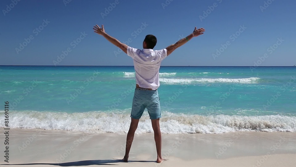 Young man standing on beach with outstretched hands Young man standing on beach with outstretched hands
