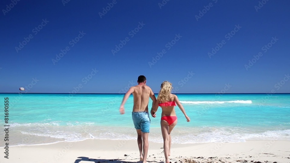 Young couple running in to the ocean 