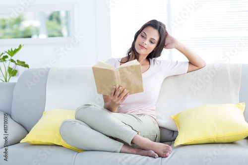 brunette relaxing and reading a book on the couch