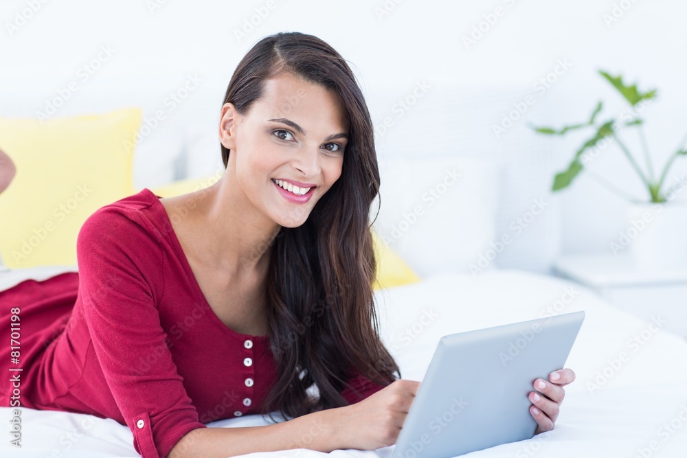 Pretty brunette using her tablet pc lying on her bed Pretty brunette using her tablet pc lying on her bed