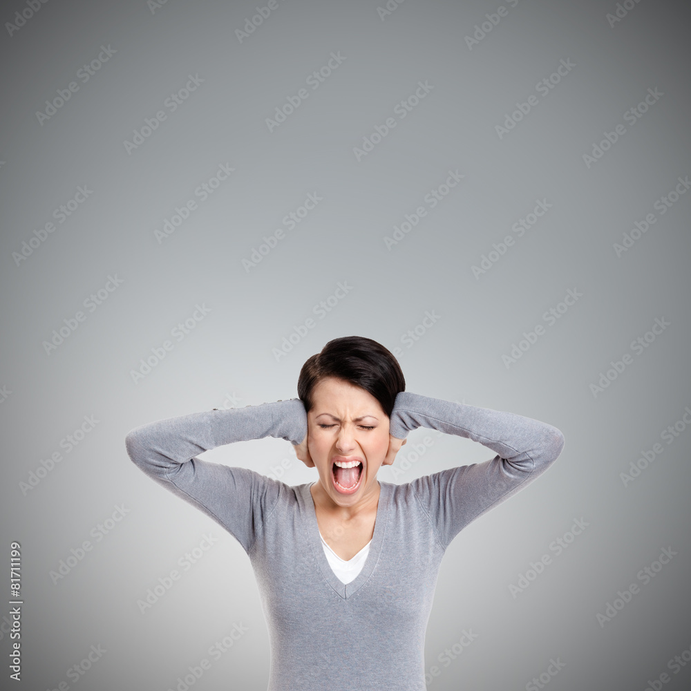 Closing ears with hands and screaming, isolated on grey Closing ears with hands and screaming, isolated on grey