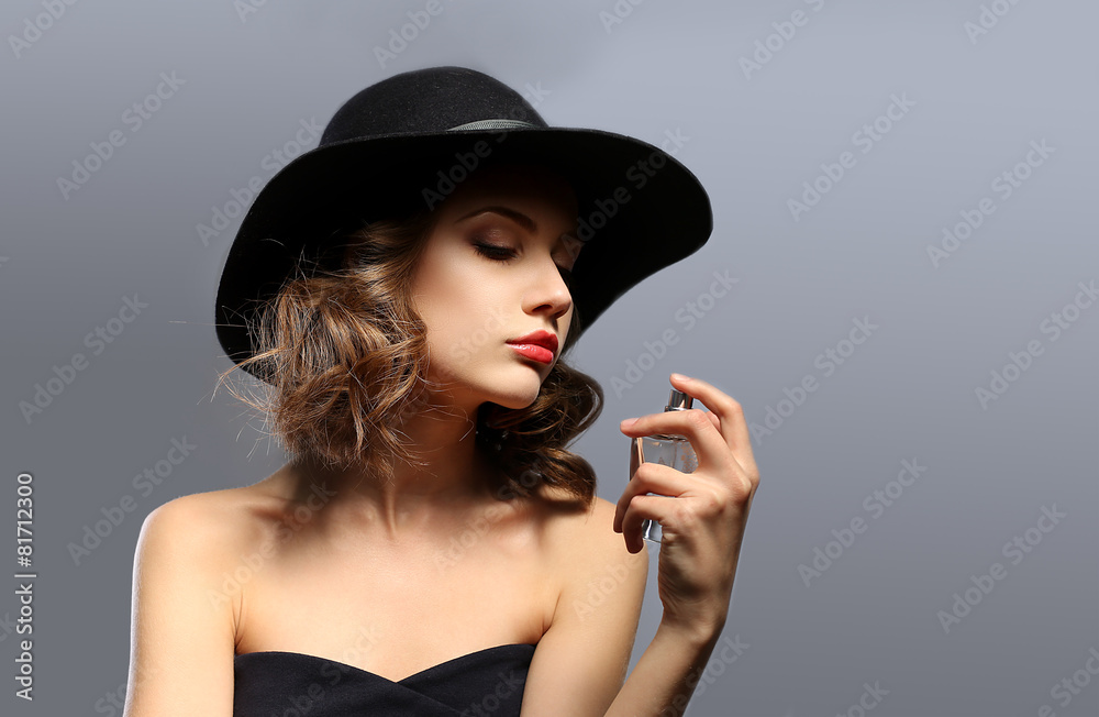 Beautiful woman with perfume bottle on gray background Beautiful woman with perfume bottle on gray background