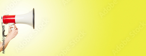 Hand hält Megafon vor Hintergrund in gelb