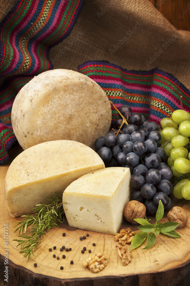 Organic cheese and grapes with walnuts and pepper on wooden log Organic cheese and grapes with walnuts and pepper on wooden log