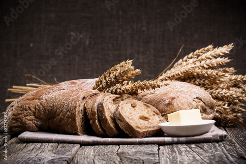 Tasty bread with wheat on wooden background.