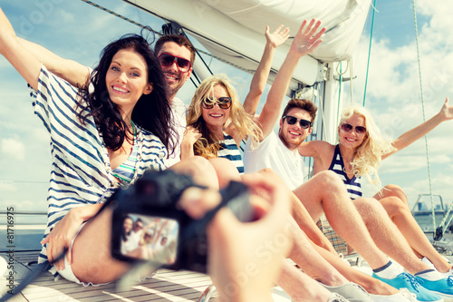 smiling friends photographing on yacht