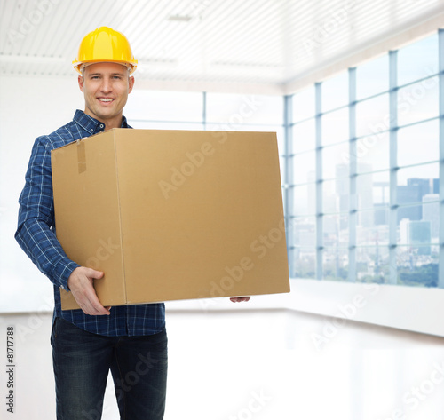 smiling male builder in helmet with cardboard box