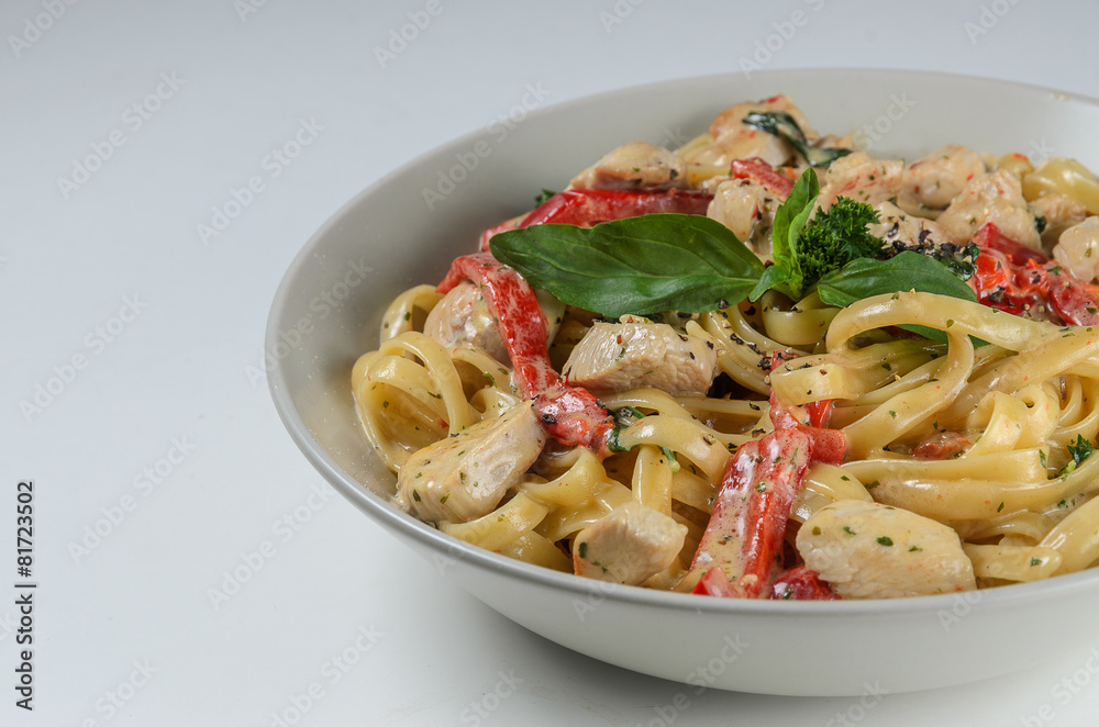 Bowl of pasta with chicken and capcicum served with fresh basil Bowl of pasta with chicken and capcicum served with fresh basil