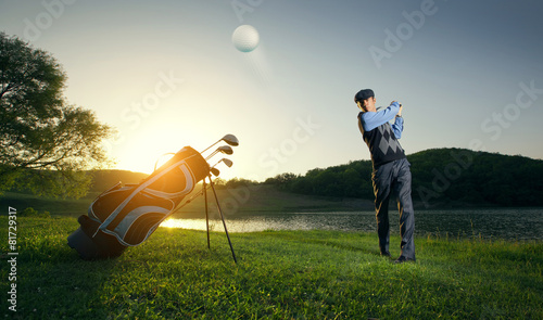 Golfer makes stroke at ball. Play golf on a green field
