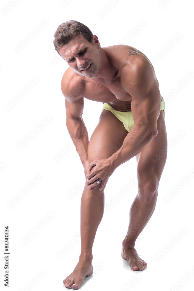 Muscular handsome man holding his leg and knee in pain