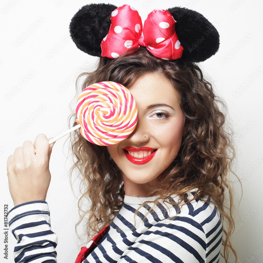 young curly woman with mouse ears holding lollipop