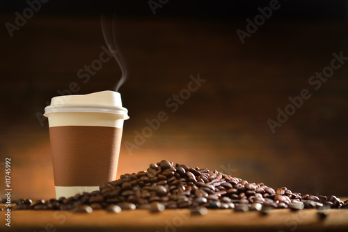 Paper cup of coffee  and coffee beans on old wooden background