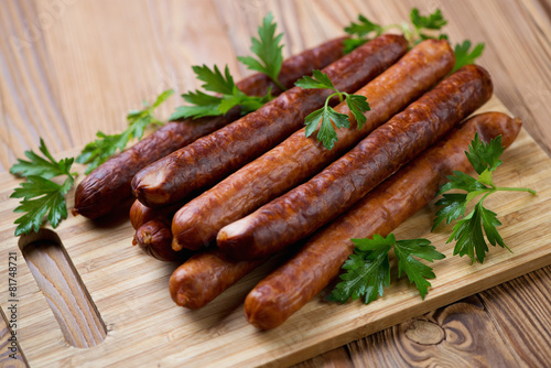 Sausages with fresh parsley on a wooden chopping board, close-up
