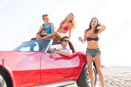 friends group at beach in sports car convertible