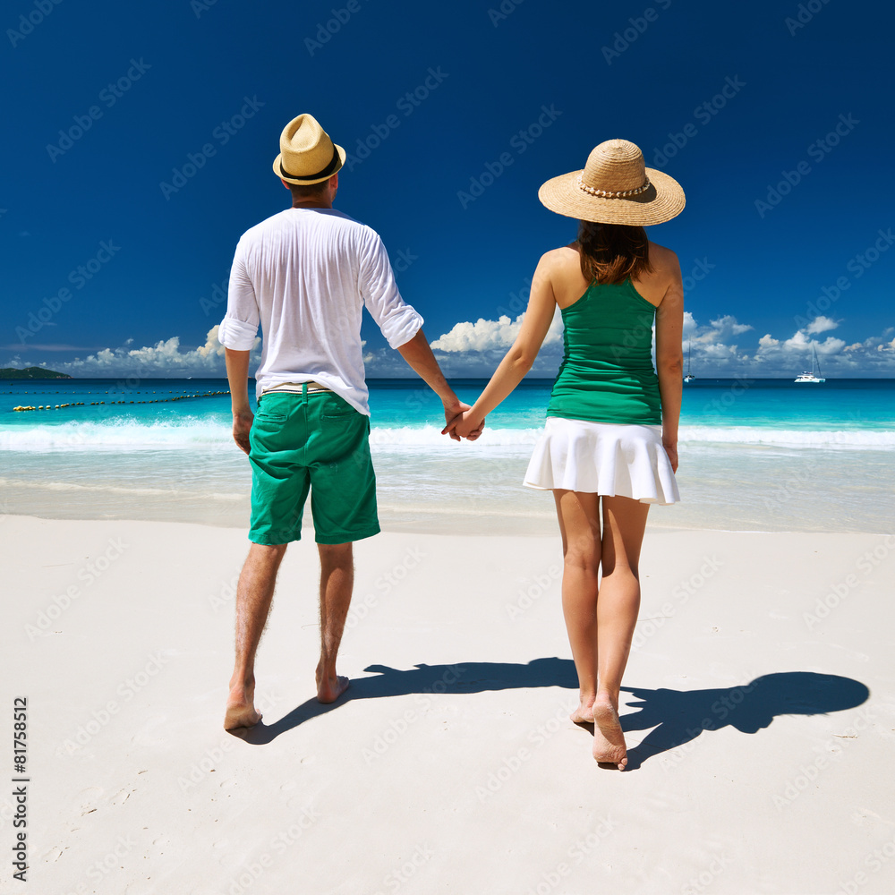 Couple in green walking on a beach at Seychelles Couple in green walking on a beach at Seychelles