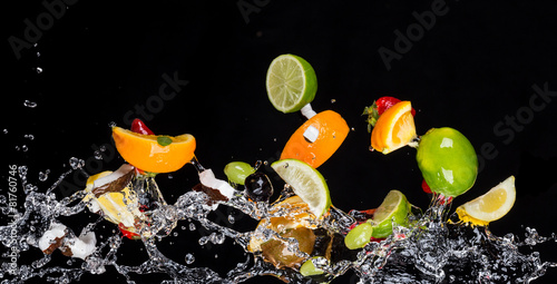 Mix of fruits with water splashes on black