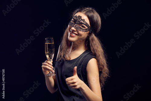Happe woman in mask holding glass with champagne