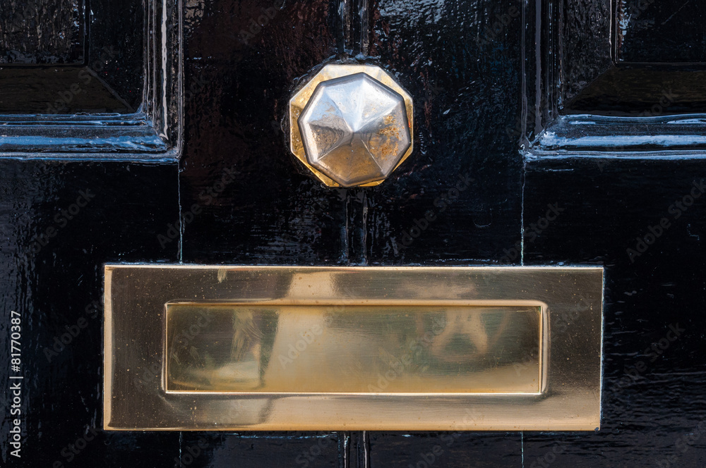 Metal mailbox and door knob on a black painted door
