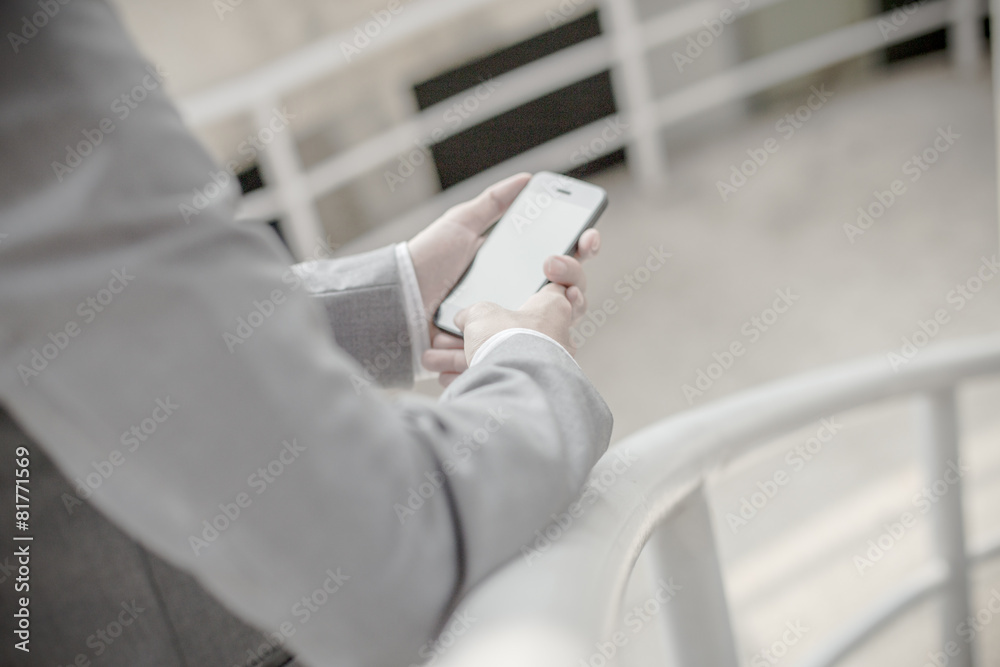 Young businessman using a phone sitting on the stairs