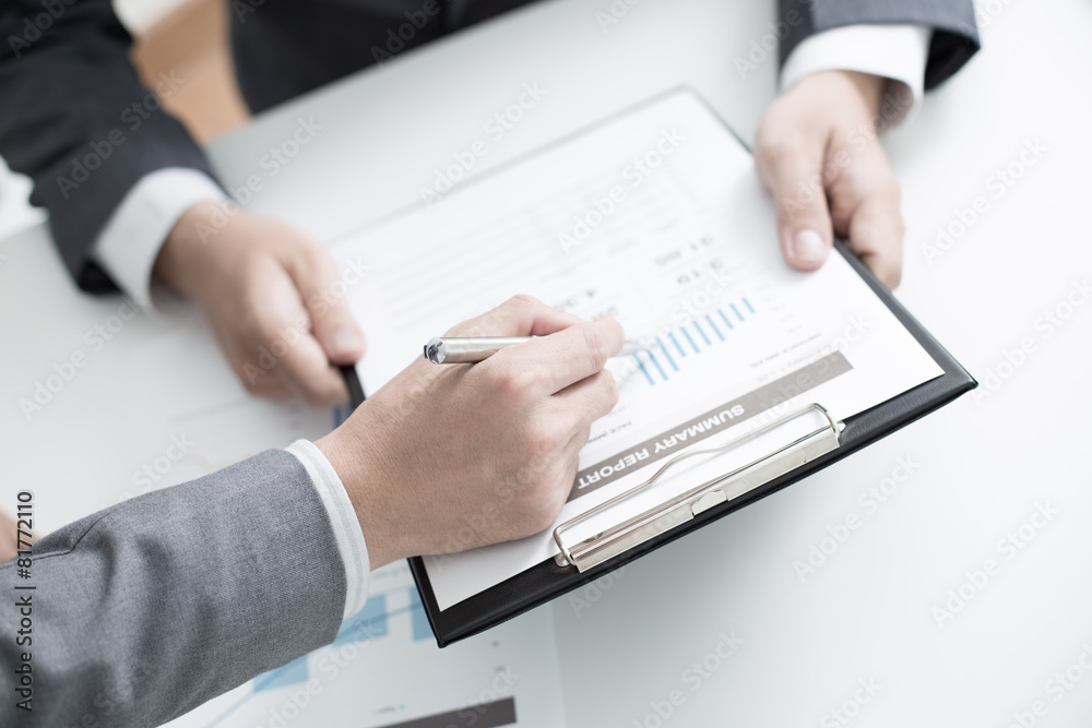 Two businessmen looking at report and having a discussion in off Two businessmen looking at report and having a discussion in off