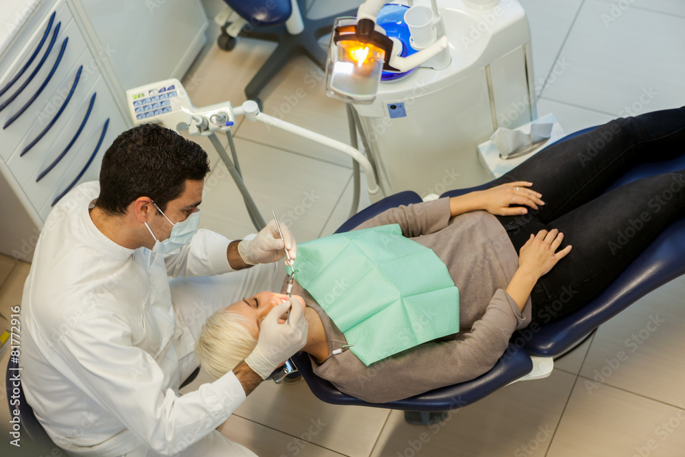 Obraz premium top view of caucasian dentist doing his job on a young blonde wo