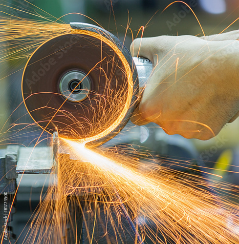 Worker cutting metal with grinder. Sparks while grinding iron