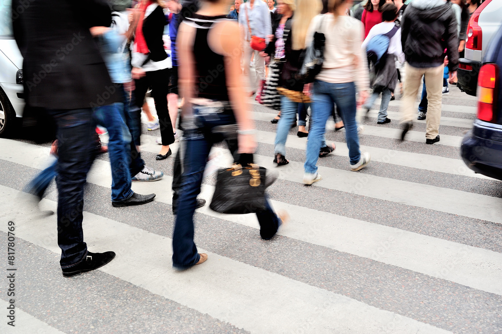 Motion blurred pedestrians crossing sunlit street