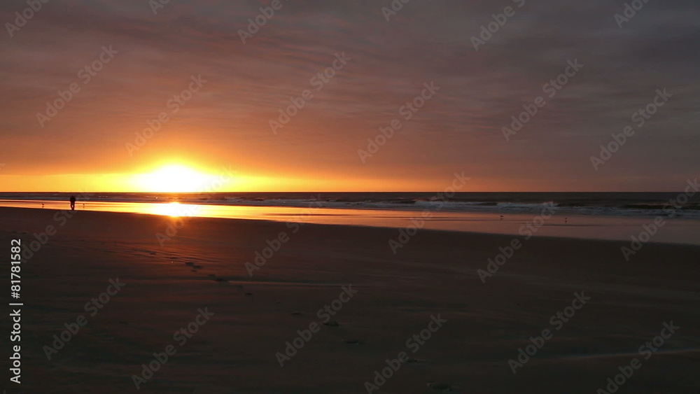 a man walking in the distance along the beach at sunrise a man walking in the distance along the beach at sunrise