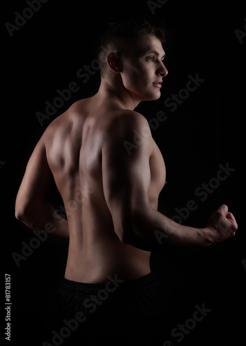 fitness athletic man showing her muscular back over black backg