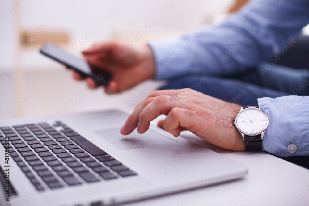 Obraz premium Businessman using laptop and mobile phone