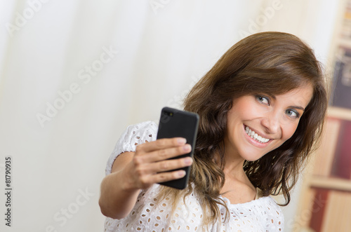 young beautiful hispanic woman using her cell phone taking a