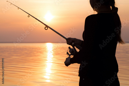 young girl fishing at sunset near the sea