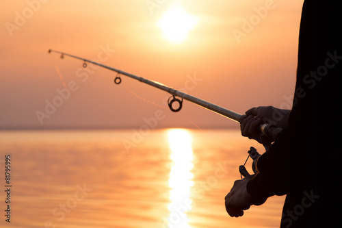 silhouette of a girl on the bank of the river with a fishing rod