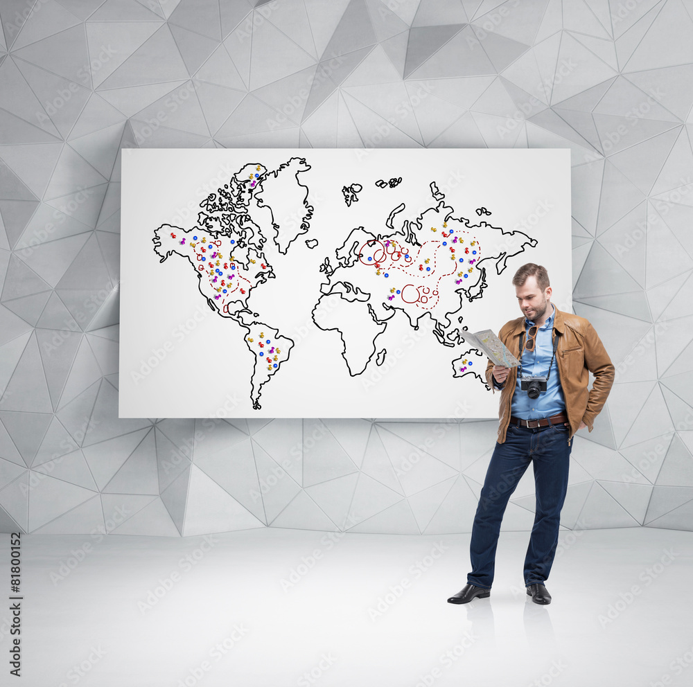 Handsome tourist is examining the map in front of whiteboard Handsome tourist is examining the map in front of whiteboard
