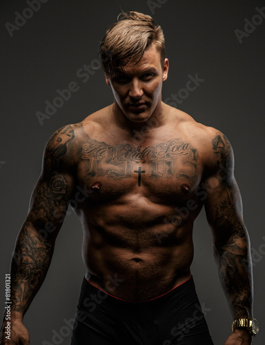 Tattooed muscular guy posing on gray background