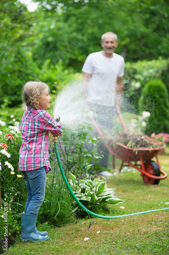 Mädchen spielt mit Gartenschlauch