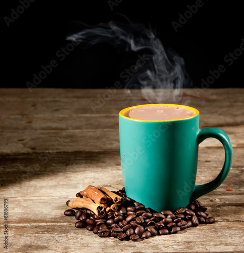 coffee cup, coffee beans and cinnamon sticks on dark background